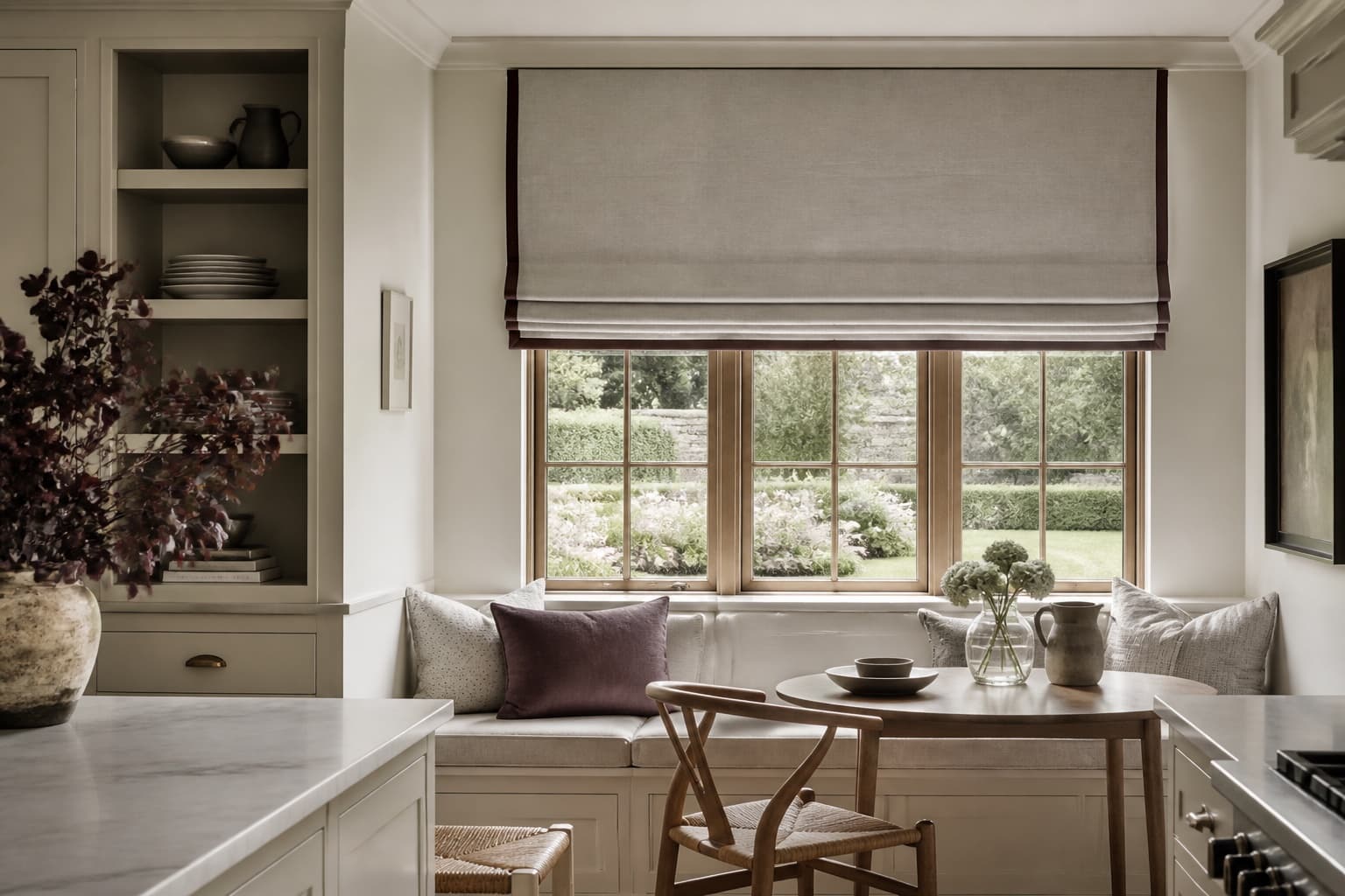 Tailored Roman blind above a window seat in a refined kitchen